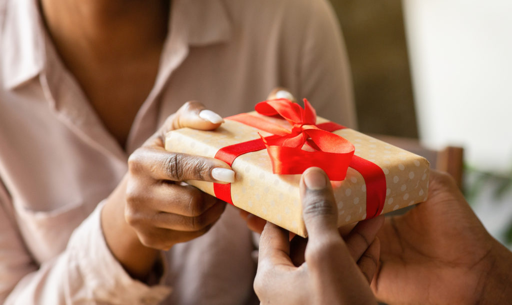 Closeup of a young couple's hands  exchanging anniversary gifts