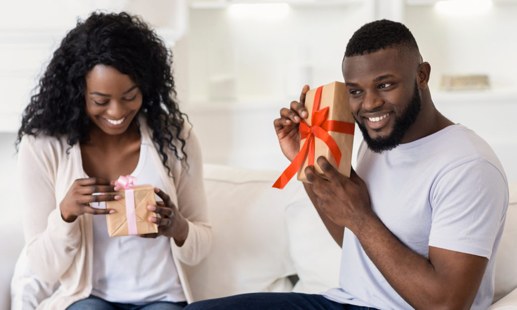 Husband and wife exchanging anniversary gifts at home