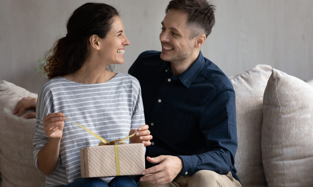 Happy woman unwrapping an anniversary gift from her loving husband.