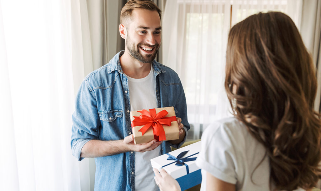 Loving couple at home, celebrating their anniversary with a gift box exchange