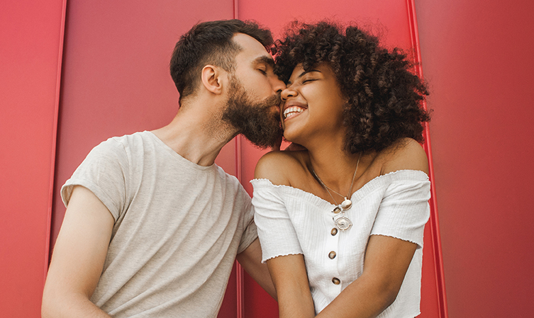 Low angle view of handsome young man kissing his smiling wife on the cheek