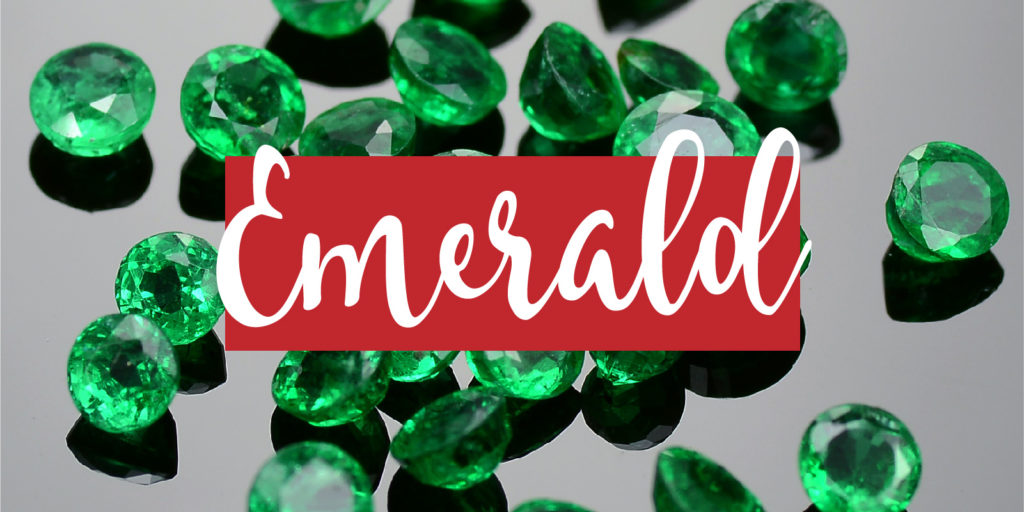 Close up of a pile of cut emerald gemstones on a dark background with a text overlay that reads "emerald'