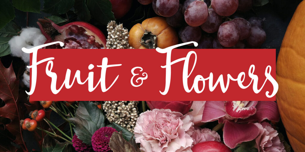 An overhead shot of miscellaneous fruits and flowers with a text overlay that reads "fruit & flowers" 