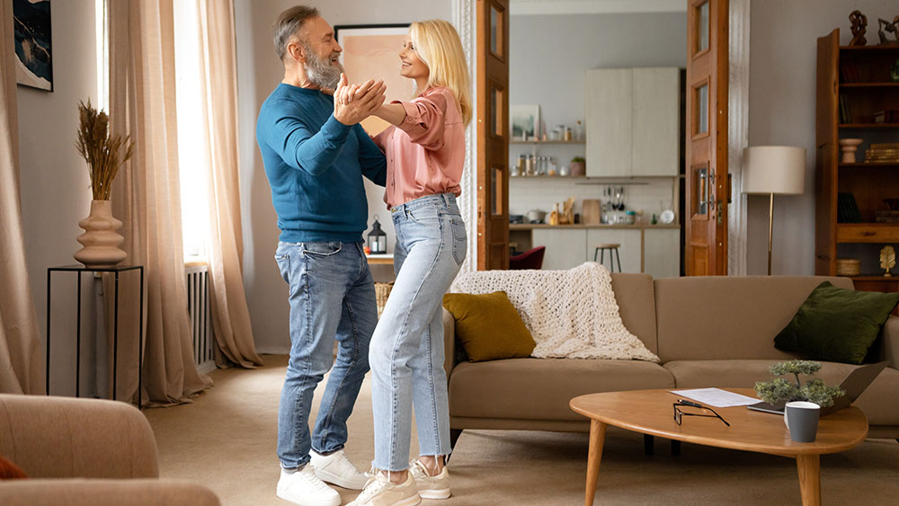 Older couple smiling and dancing in their living room with Mid-Century Modern furnishings