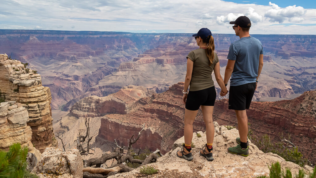 Loving couple standing on rock with scenic view from Skeleton Point on South Kaibab hiking trail at South Rim, Grand Canyon National Park, Arizona, USA.